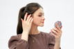 a woman in a brown shirt is holding a cell phone